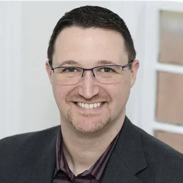 A man with glasses and a suit jacket.